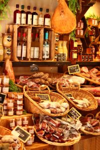 Discover a vibrant selection of traditional French charcuterie and wines at a charming market in Montblanc, France.