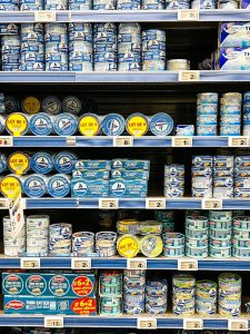 Brightly colored sardine and tuna cans on a supermarket shelf in Calais, France.