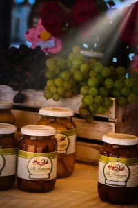 A vibrant display of green and red grapes alongside jars of preserves on a market table in Tarija, Bolivia.