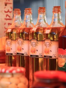 Multiple bottles of honey with honeycomb labels on display at a market.